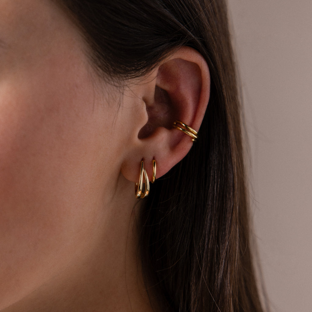 Close up of a model wearing our Oval Duo Hoops in Gold, styled with our Claw Ear Cuffs
