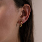 Close up image of a model wearing our Tiny Teardrop Huggies in Gold