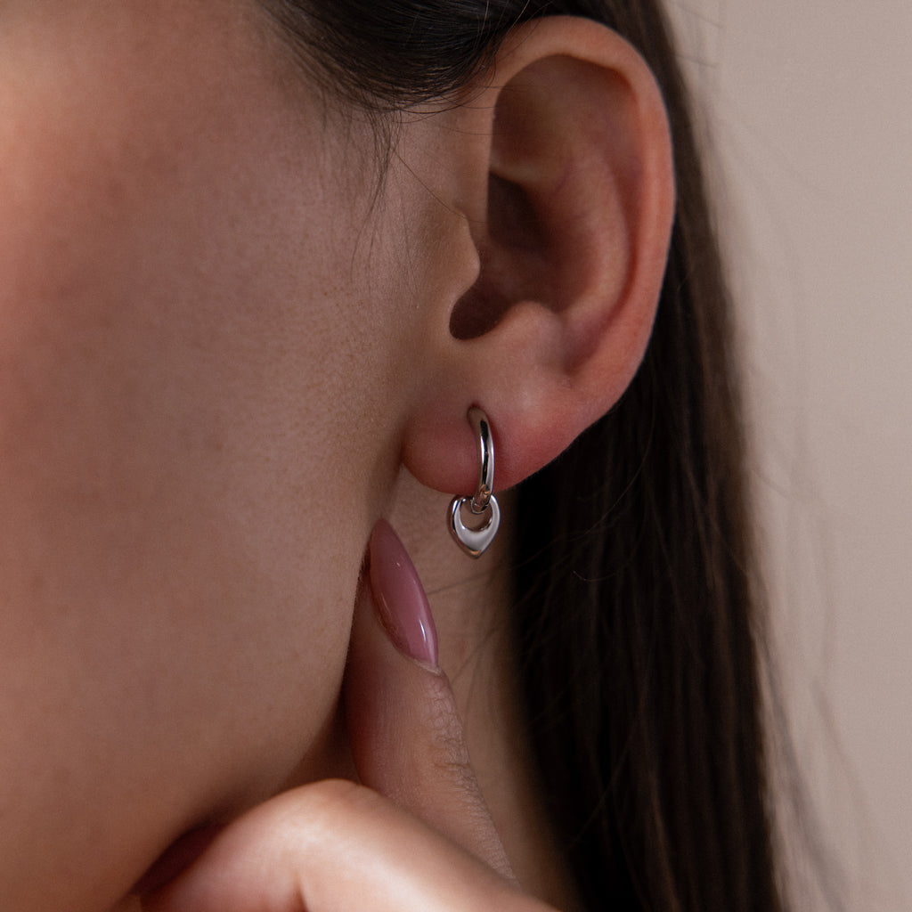 Close up of a model wearing our Tiny Teardrop Huggies in White Gold