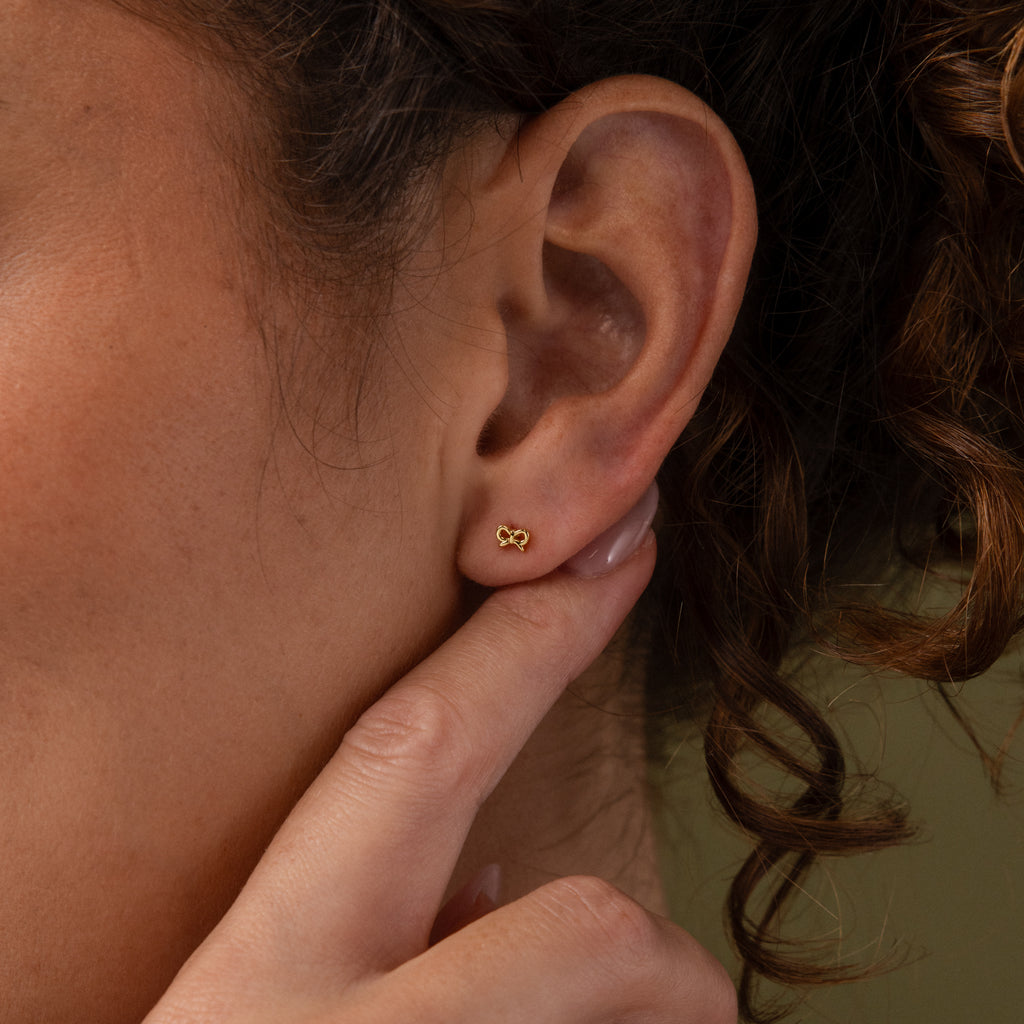 Model wearing our Tiny Bow Flatback Studs in Gold