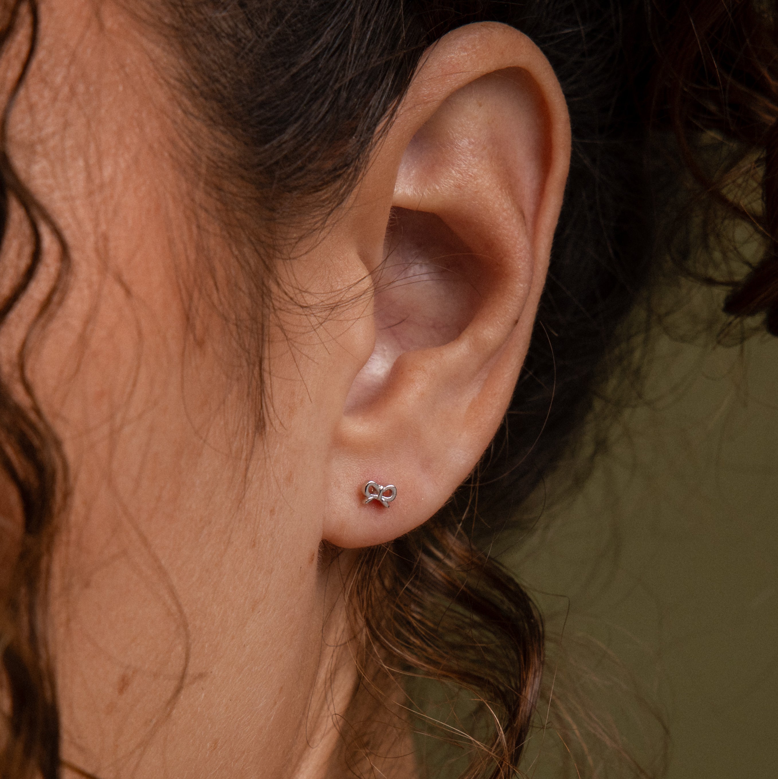 Close-up of a model wearing our Tiny Bow Flatback Studs in Silver