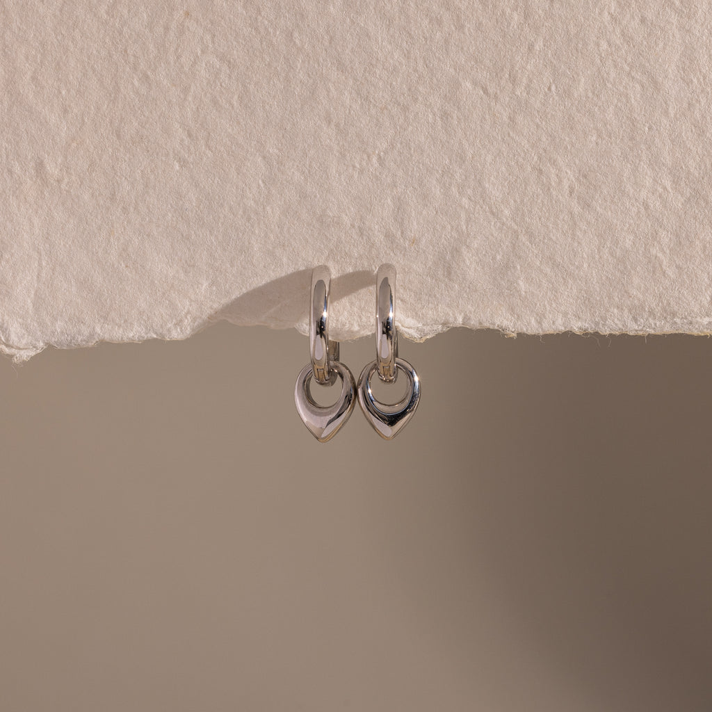 Flatlay of our Tiny Teardrop Huggies in White Gold