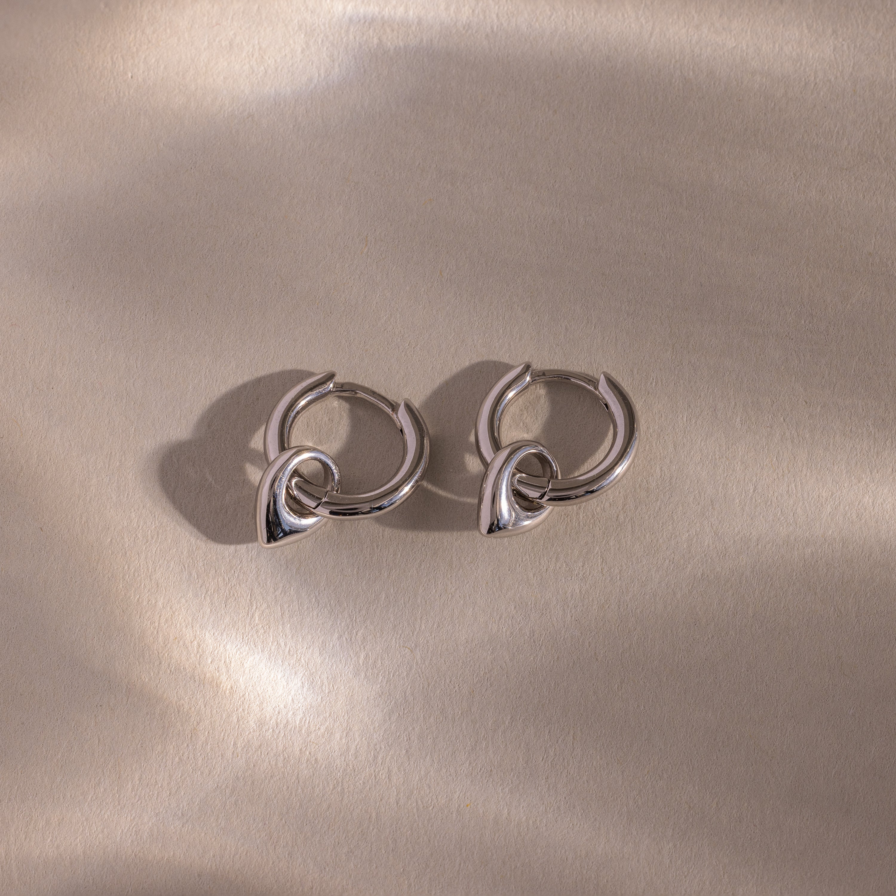 Close up flatlay of our Tiny Teardrop Huggies in White Gold