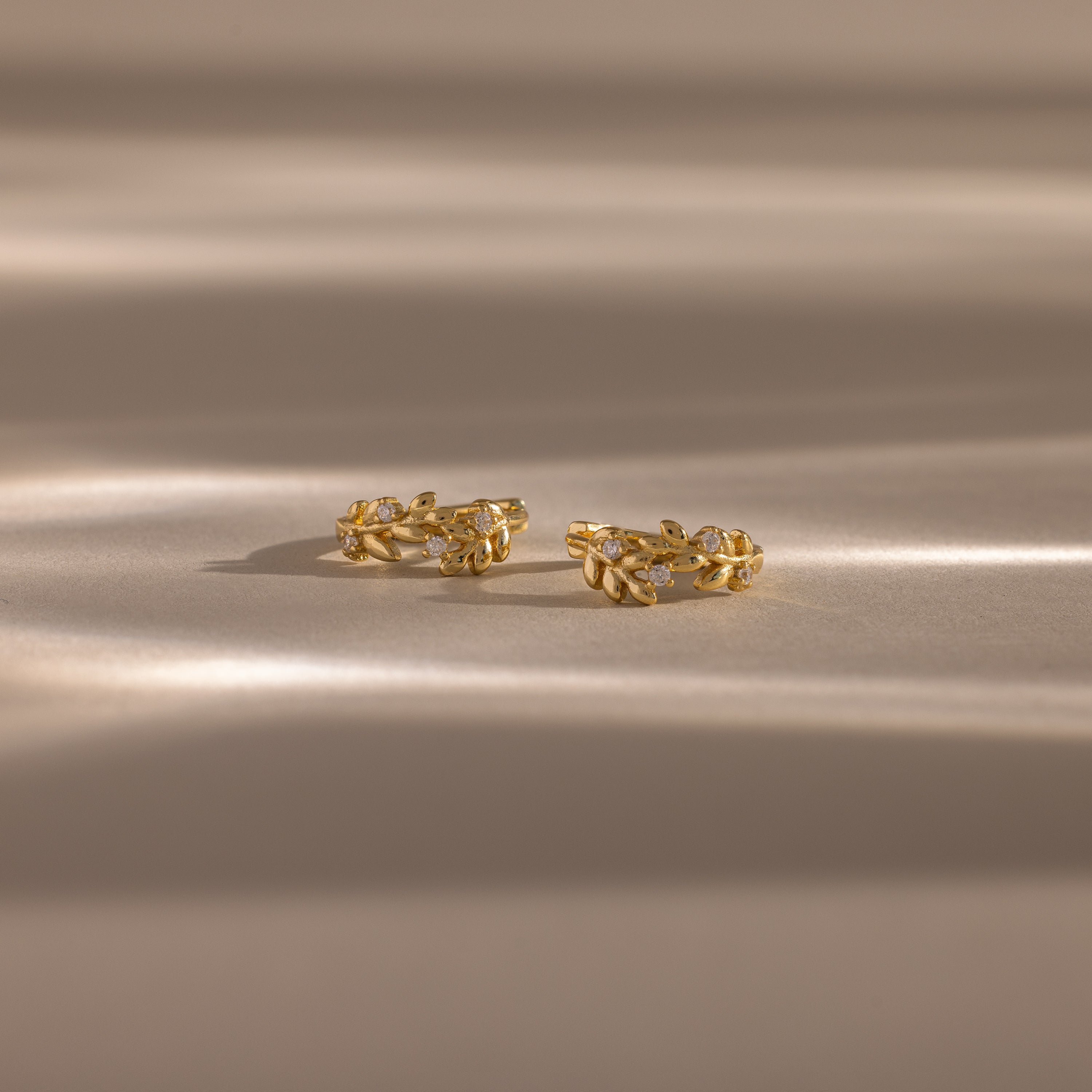 Flatlay image of our Diamond Leaf Hoops in Gold