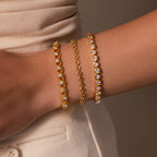 The wrist is adorned with the Diamond Heart Rope Bracelet, featuring sparkling diamond hearts, styled with cream-colored clothing.