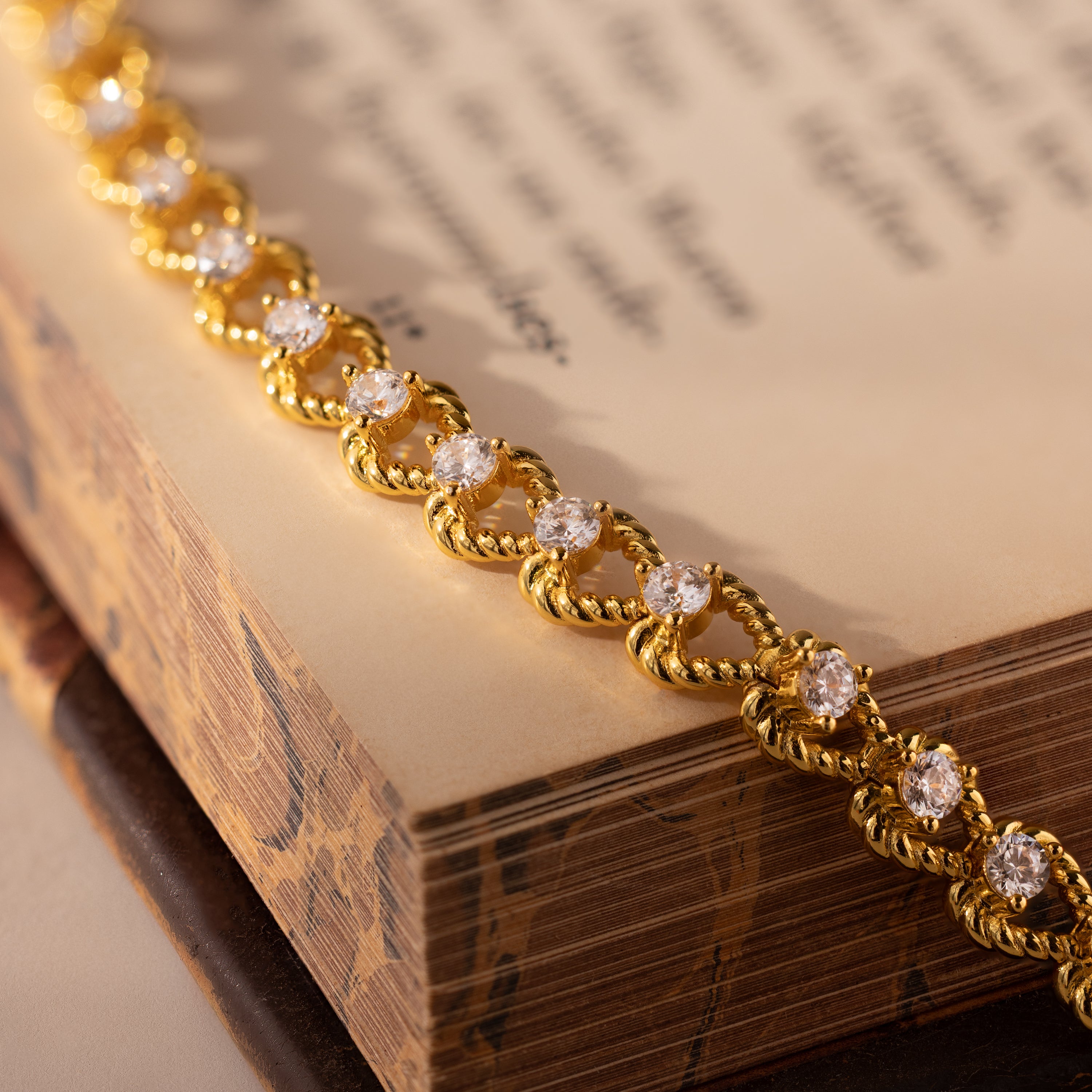 The Diamond Heart Rope Bracelet glimmers atop the pages of an open book, its sparkling hearts shining above the softly blurred text.