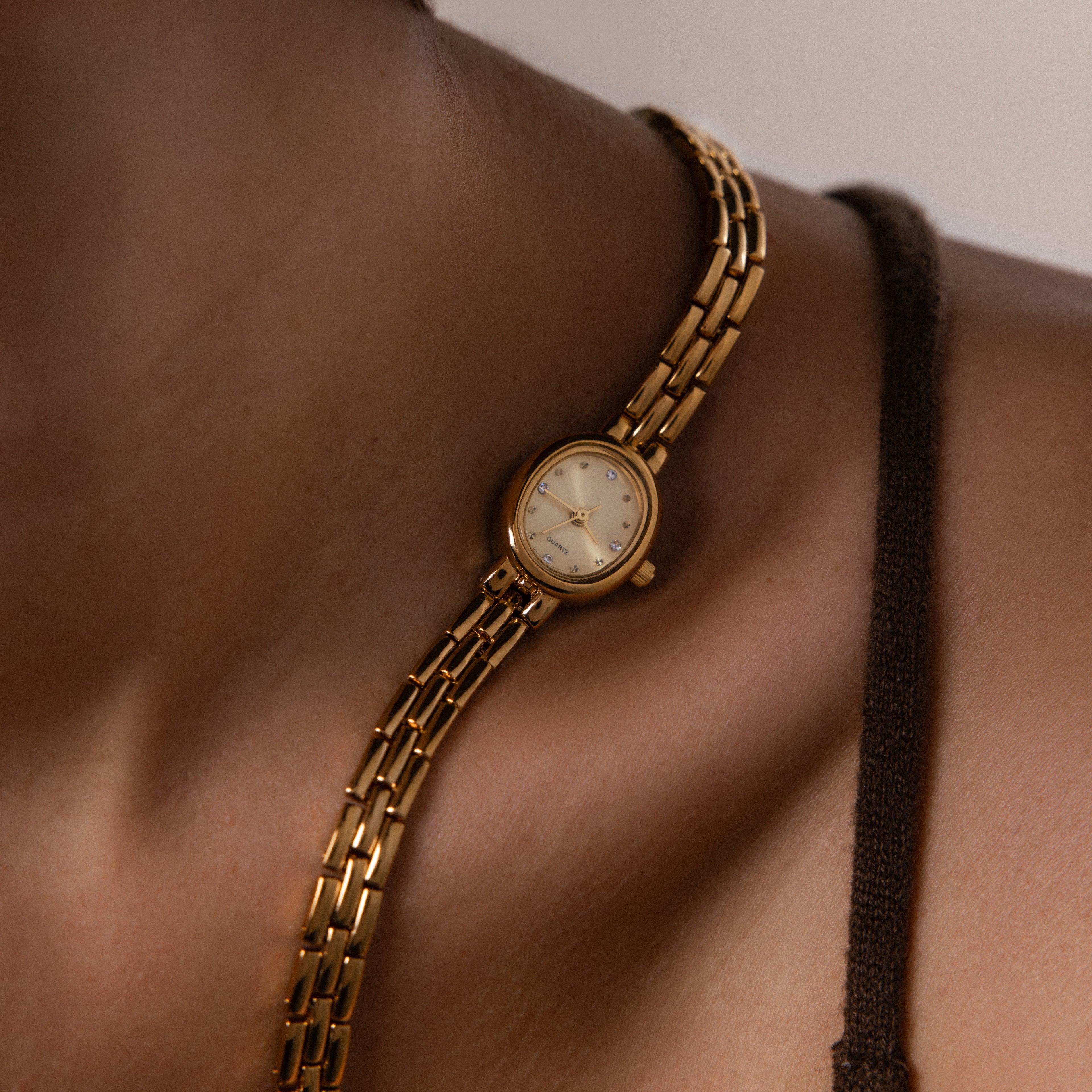 Stylized photo of our Cobblestone Timepiece watch laid on a model's collarbone