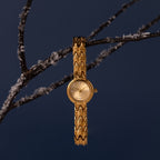 Flatlay image of our Wavy Link Timepiece watch on a branch against a blue background