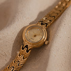 Close up of our Wavy Link Timepiece watch on a beige surface
