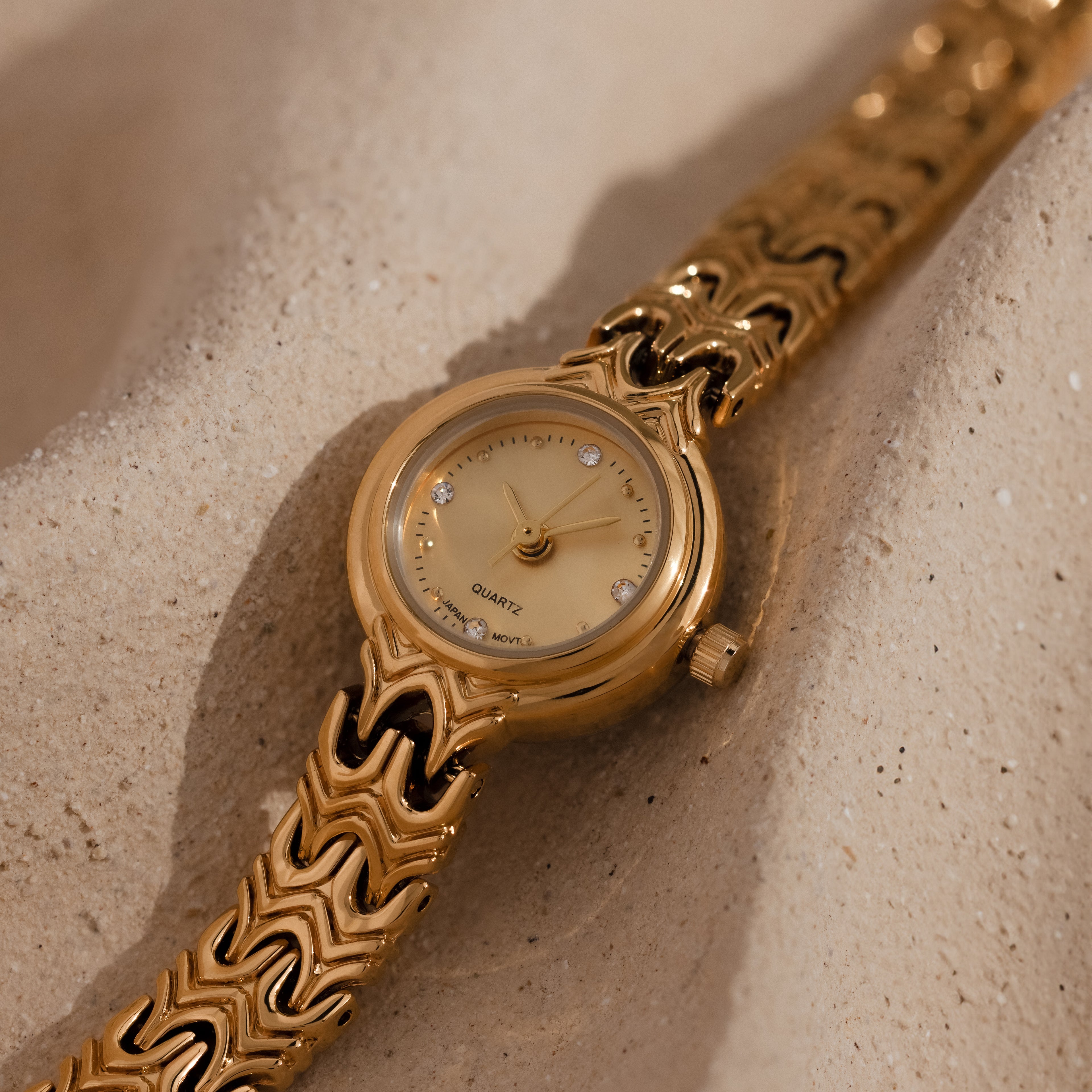 Close up of our Wavy Link Timepiece watch on a beige surface