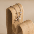 The Viper Snake Charm in Sterling Silver hangs on a beige, curved textured display against a soft background—ideal for those seeking transformation jewelry with distinctive elegance.