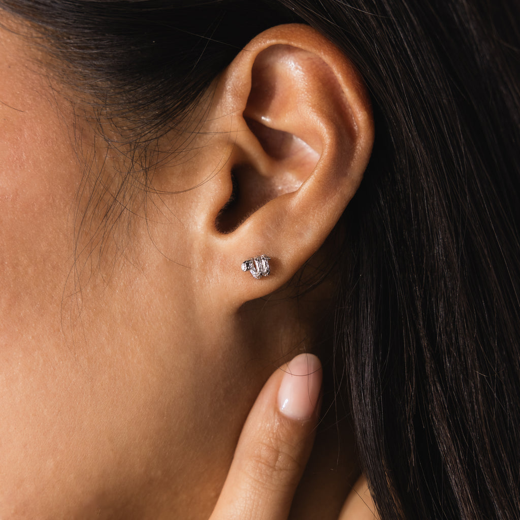 Up-close of model wearing silver 3D twisted snake stud earrings.