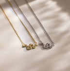 Gold and silver snake charm necklaces with pavé details, displayed side by side on a neutral background.