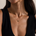 Close-up of a dainty gold serpent necklace on a model, highlighting the curved snake pendant.