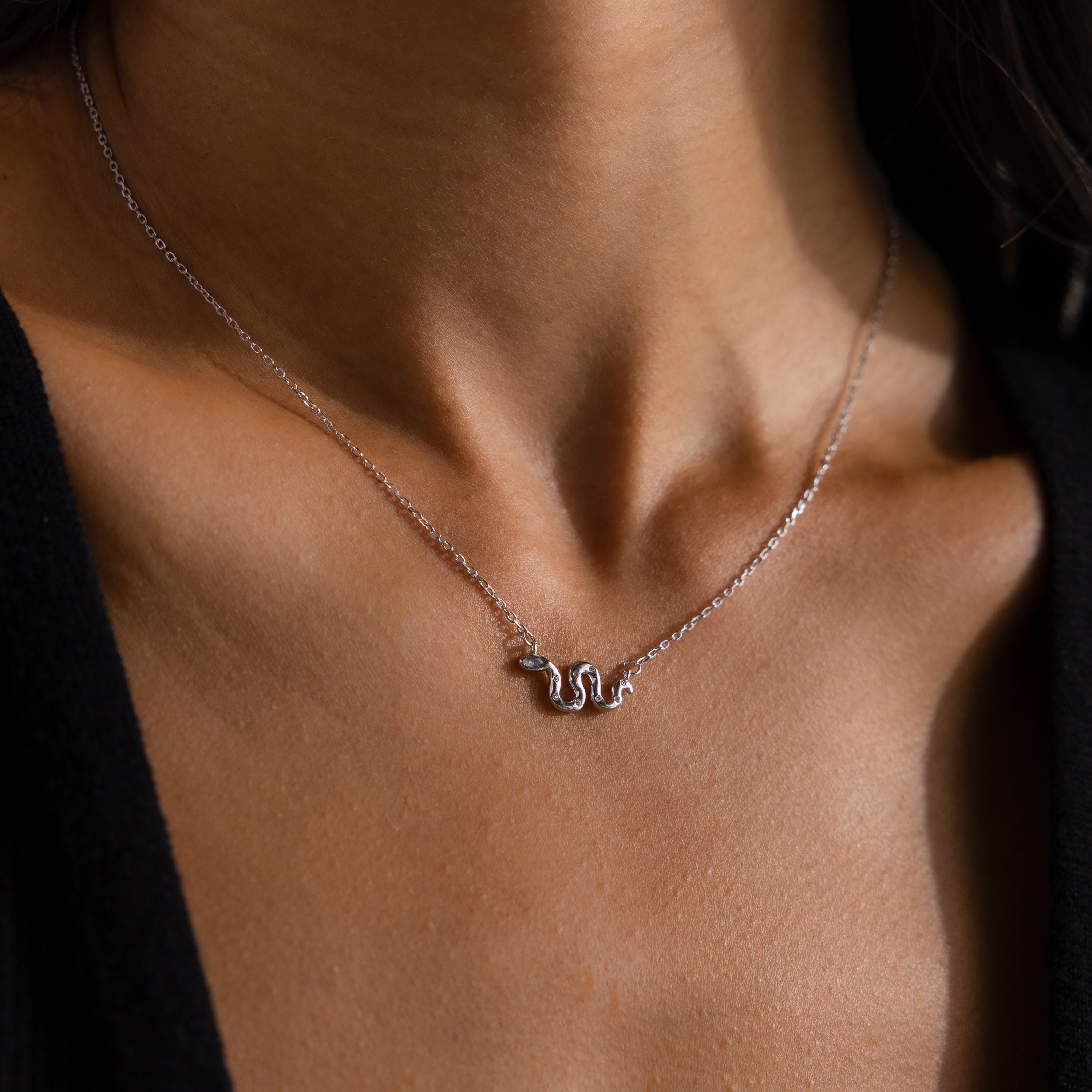 Close-up of model wearing a silver viper snake pendant necklace on a delicate chain.
