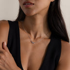 Close-up of a silver viper snake charm necklace on a model in a black v-neck top.