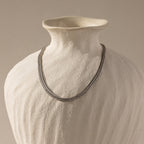 The gold mesh necklace displayed on a matte ceramic bust.