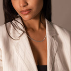 Woman wearing a white pinstripe blazer and the Bold Snake Chain Necklace, shown from shoulders to lips—a refined touch of modern jewelry.