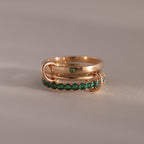 The Triple Linked Emerald Ring Set features three gold rings linked together—one plain with a green gem and two adorned with small green stones—creating a bold statement piece.