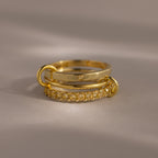 The Triple Linked Topaz Ring Set, featuring three stacked gold bands with delicate topaz accents, is displayed on a neutral background with soft lighting.