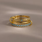 The Triple Linked Aquamarine Ring Set features beautifully stacked gold rings, including a statement piece with a blue stone and a band adorned with aquamarine gems.