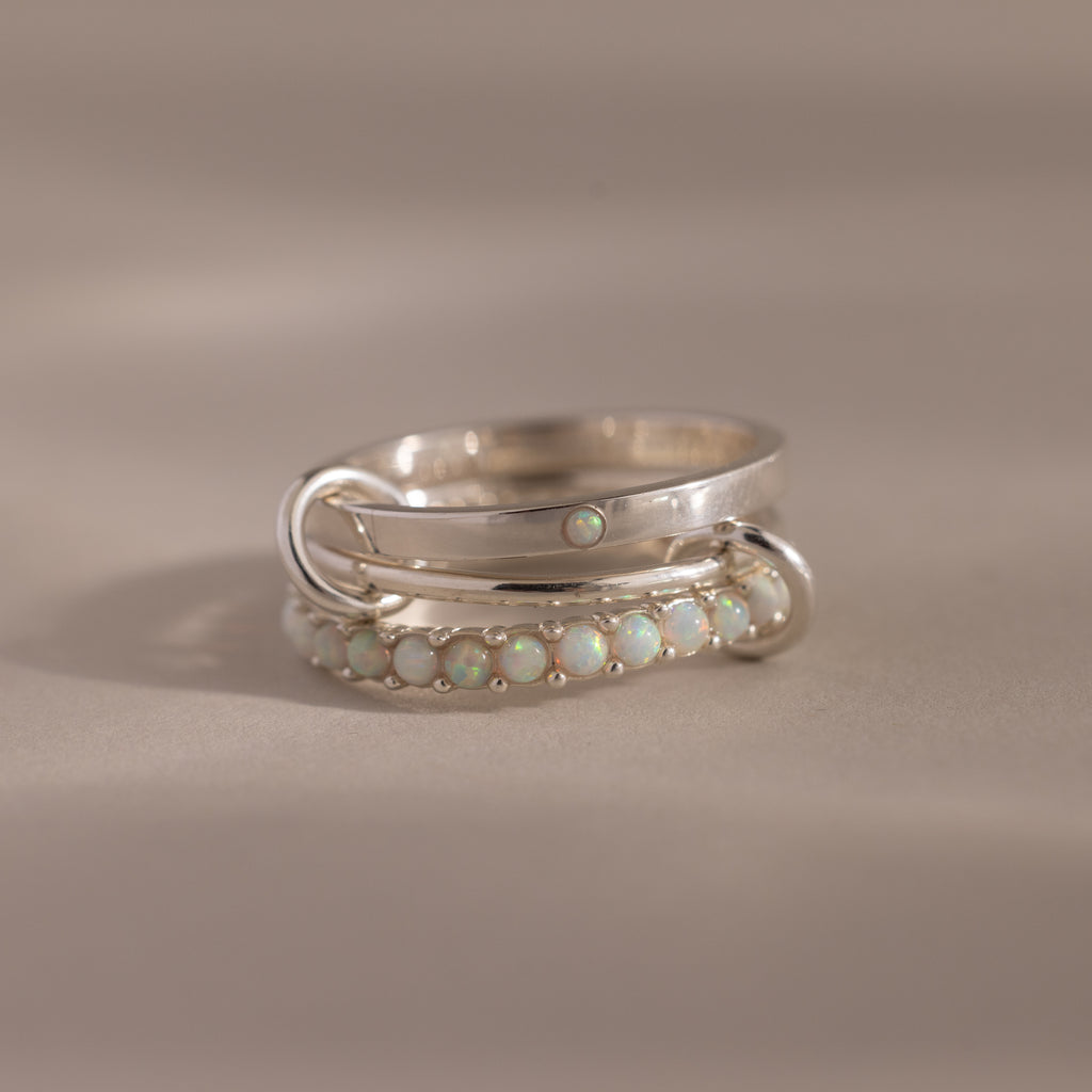 The Triple Linked Opal Ring Set features silver bands adorned with small opal stones, shown on a neutral background.