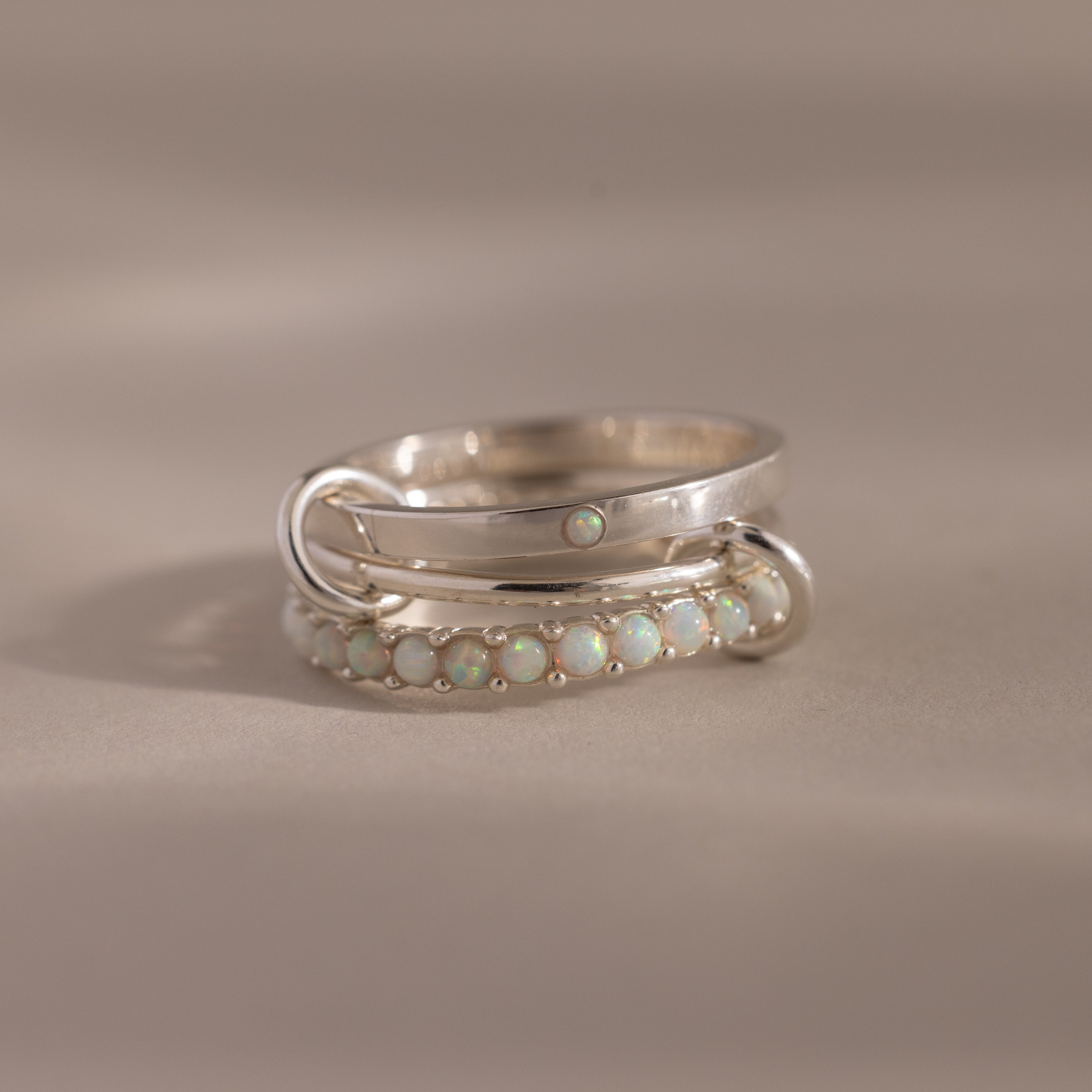 The Triple Linked Opal Ring Set features silver bands adorned with small opal stones, shown on a neutral background.