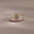 Triple Linked Alexandrite Ring Set featuring small purple gemstones and two metallic loops, displayed on a neutral background.