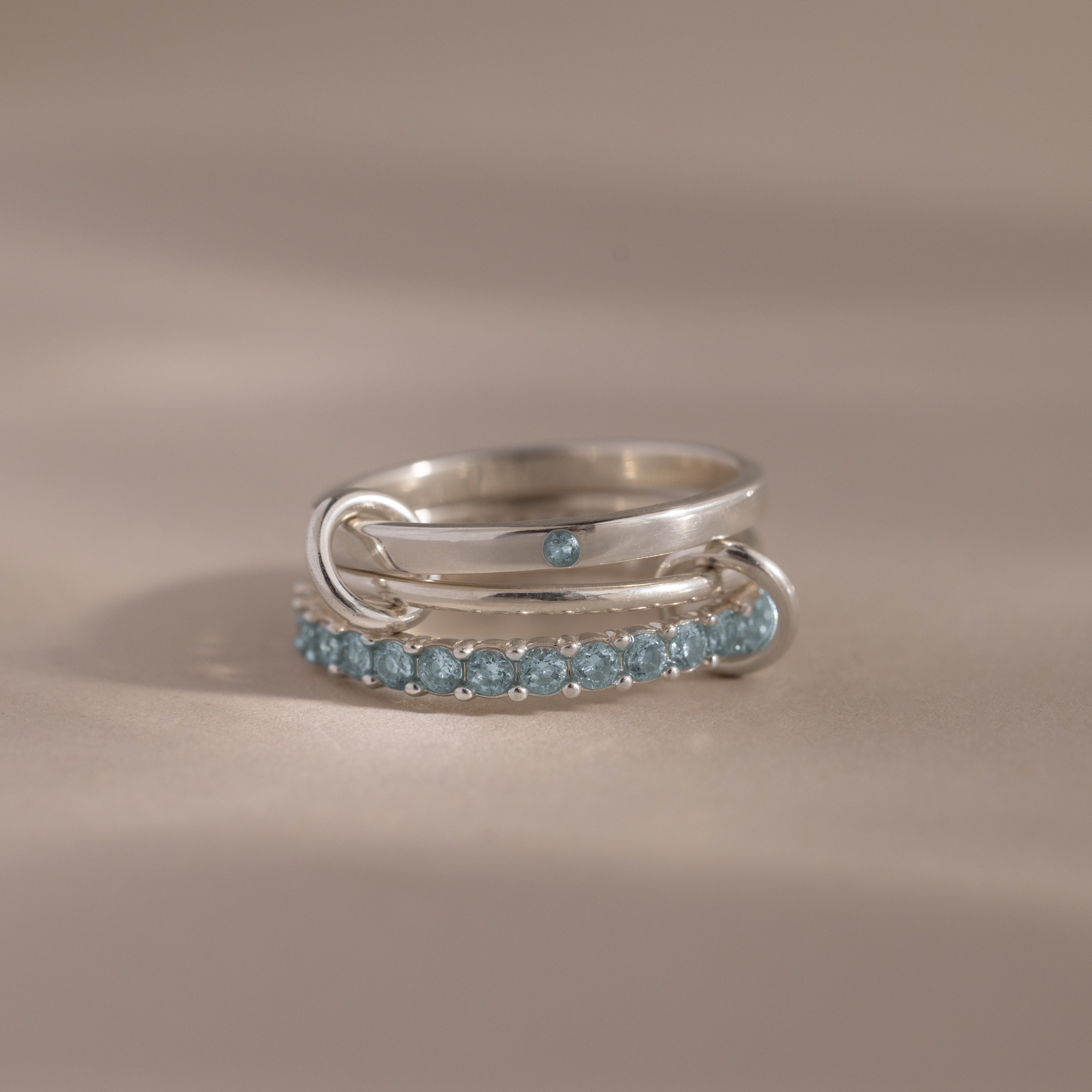 The Triple Linked Aquamarine Ring Set showcases blue gemstones on three intertwined bands, creating an elegant silver statement ring—an ideal eternity birthstone accessory for any occasion.