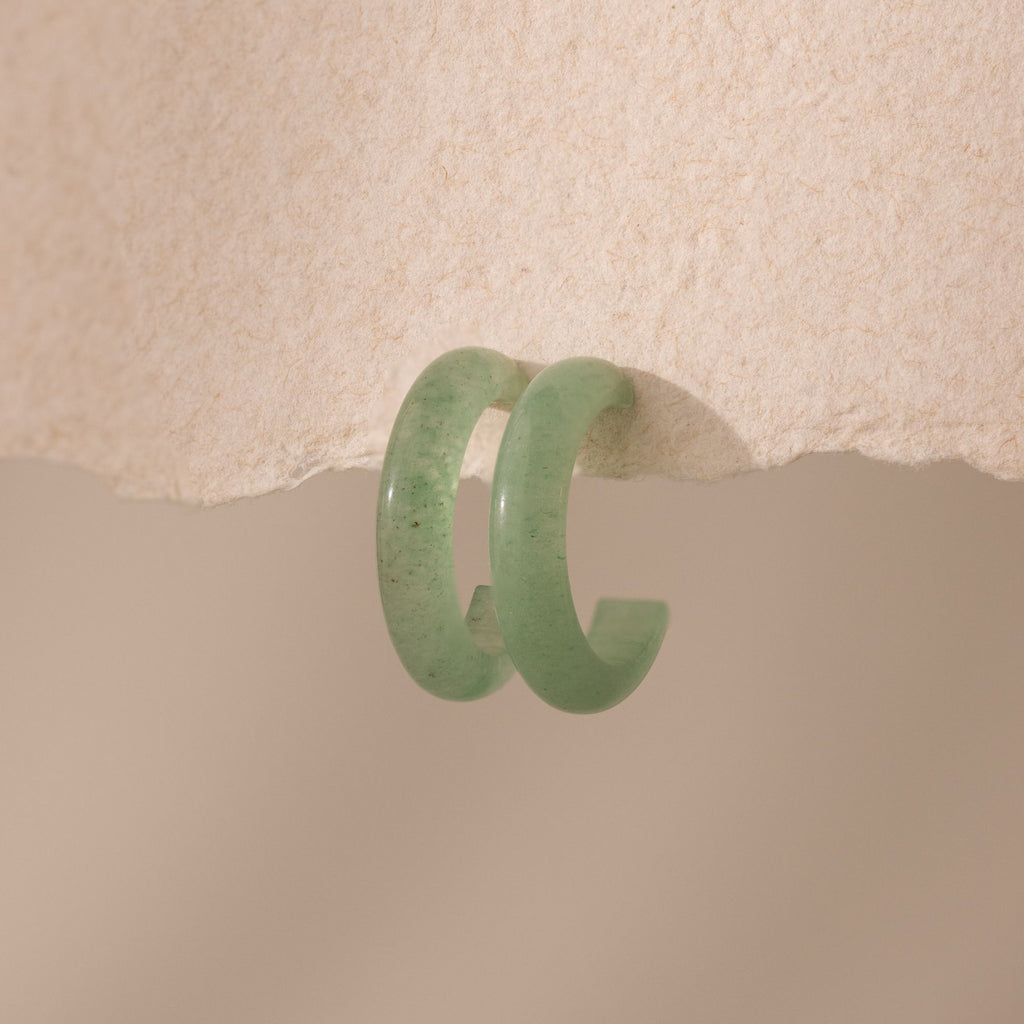 Pair of Jade Hoop Earrings, featuring a chunky hoop design with a soft green natural jade gemstone, displayed on a paper surface.