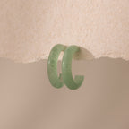 Pair of Jade Hoop Earrings, featuring a chunky hoop design with a soft green natural jade gemstone, displayed on a paper surface.
