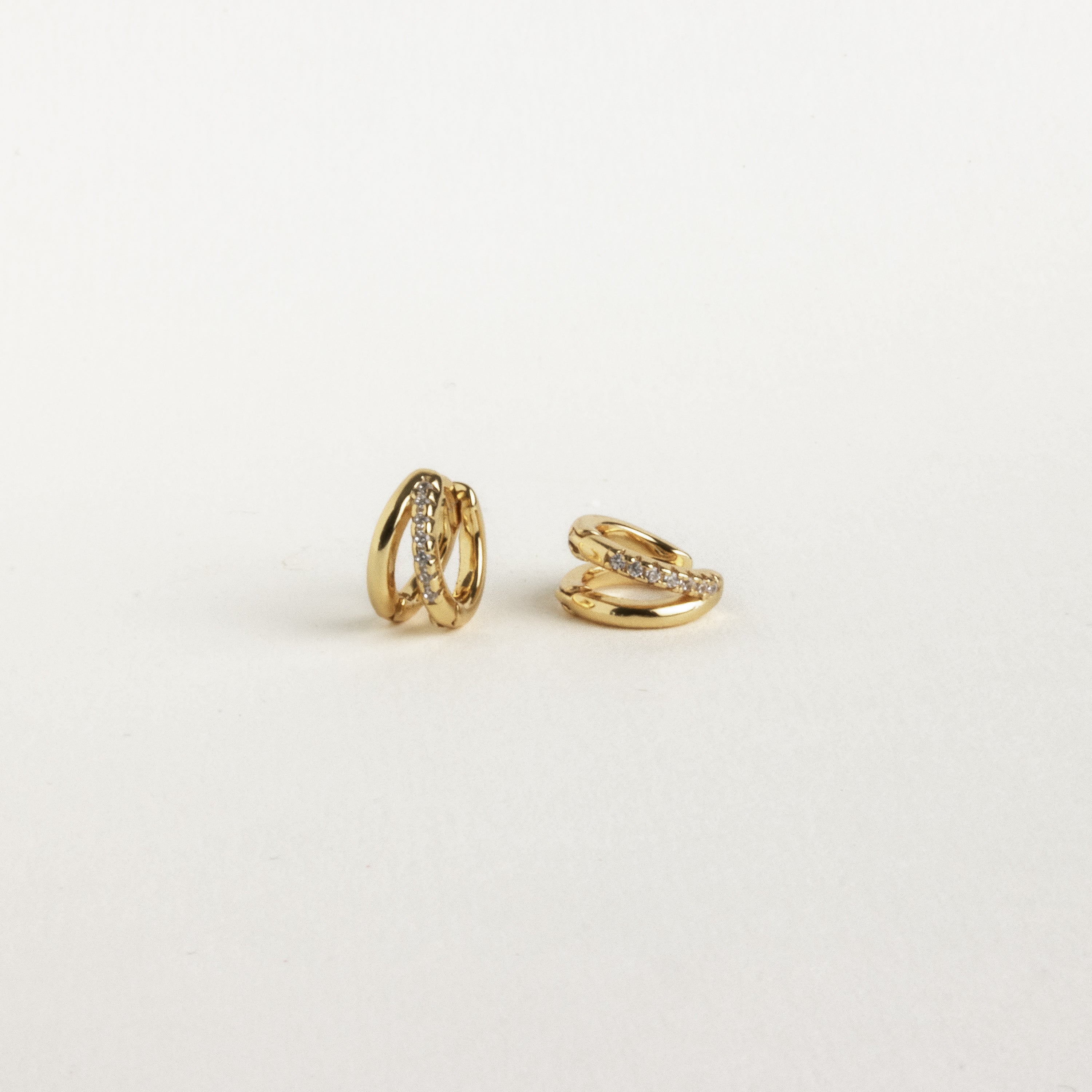 Two small gold Amelia Duo Huggies featuring embedded clear stones and pave accents, shown on a plain white background.