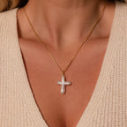 A woman wears the Baroque Pearl Cross Necklace in 18K Gold over a cream knit top, highlighting its minimalist style and elegant freshwater pearls.