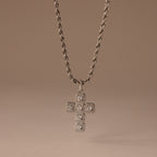 Majesty Cross Necklace in Silver featuring a diamond-encrusted cross pendant and sparkling stones, displayed on a neutral beige background.
