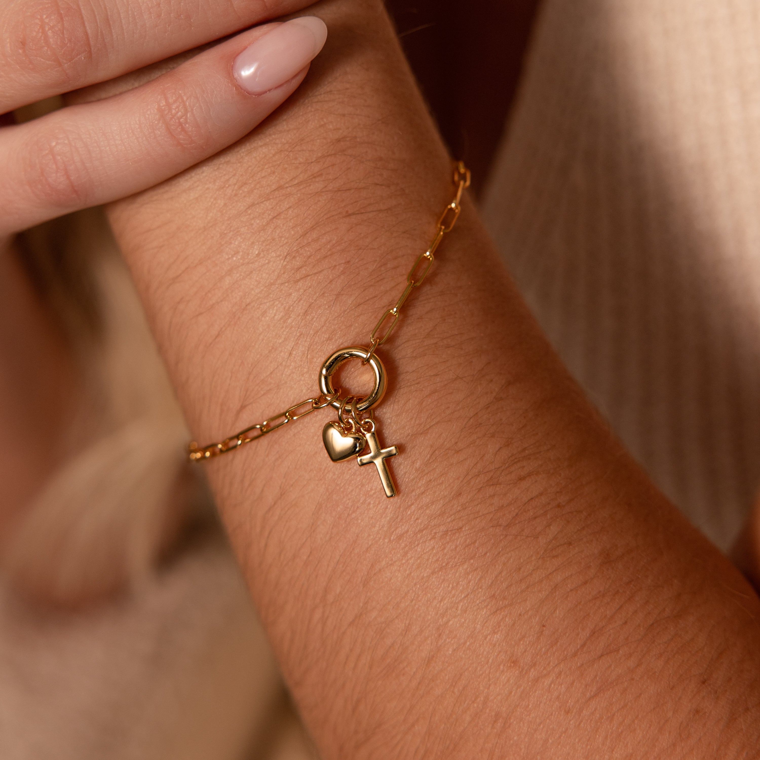 Close-up of the Cross & Heart Charm Bracelet, featuring minimalist cross and heart charms on a paperclip chain, worn on a person's wrist.