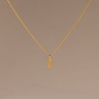 The Vintage Cross Necklace in 18K Gold features a pavé-finished, diamond-studded cross pendant displayed on a simple light brown background.