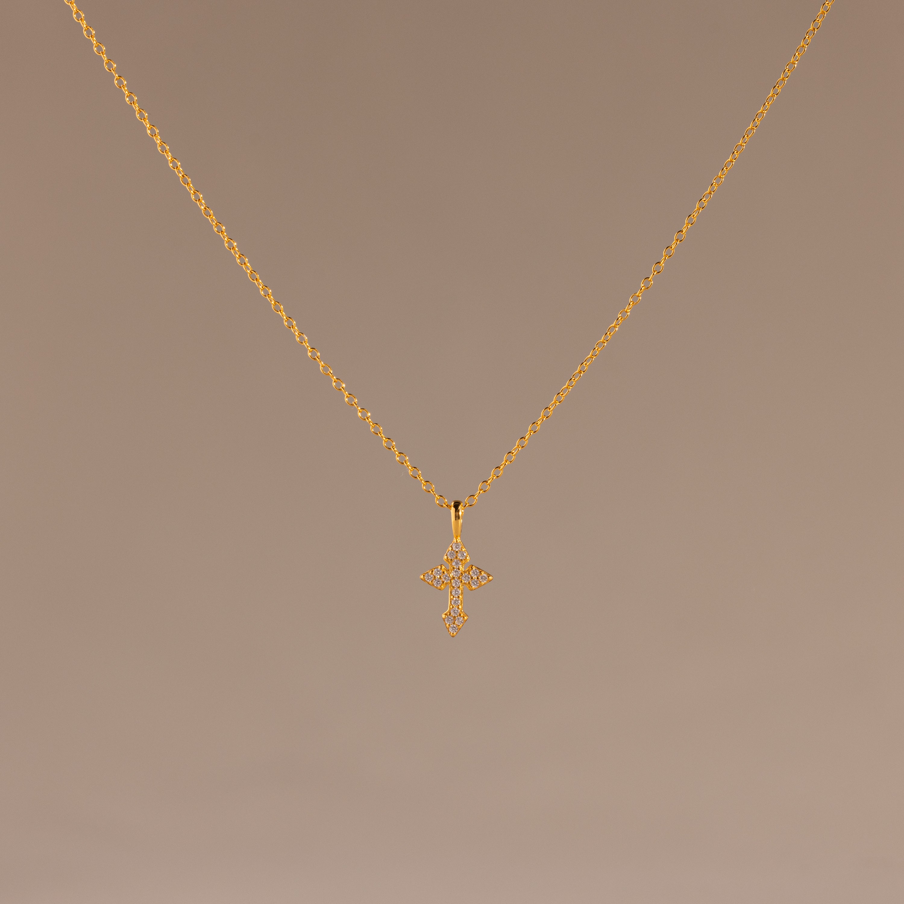 The Vintage Cross Necklace in 18K Gold features a pavé-finished, diamond-studded cross pendant displayed on a simple light brown background.