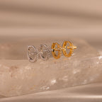 Two pairs of Diamond Cross Huggies, one in silver and one in gold, each featuring pavé stones on the cross charms, displayed on a stone slab.