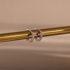 Two Diamond Cross Huggies in Silver, accented with pavé stones, dangle from a gold rod for a delicate look.