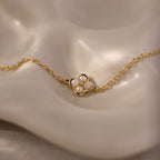 Rounded Pearl Flower Bracelet in 18K Gold features a flower-shaped pendant adorned with four small pearls—an elegant, delicate bracelet perfect for layering with your favorite accessories.