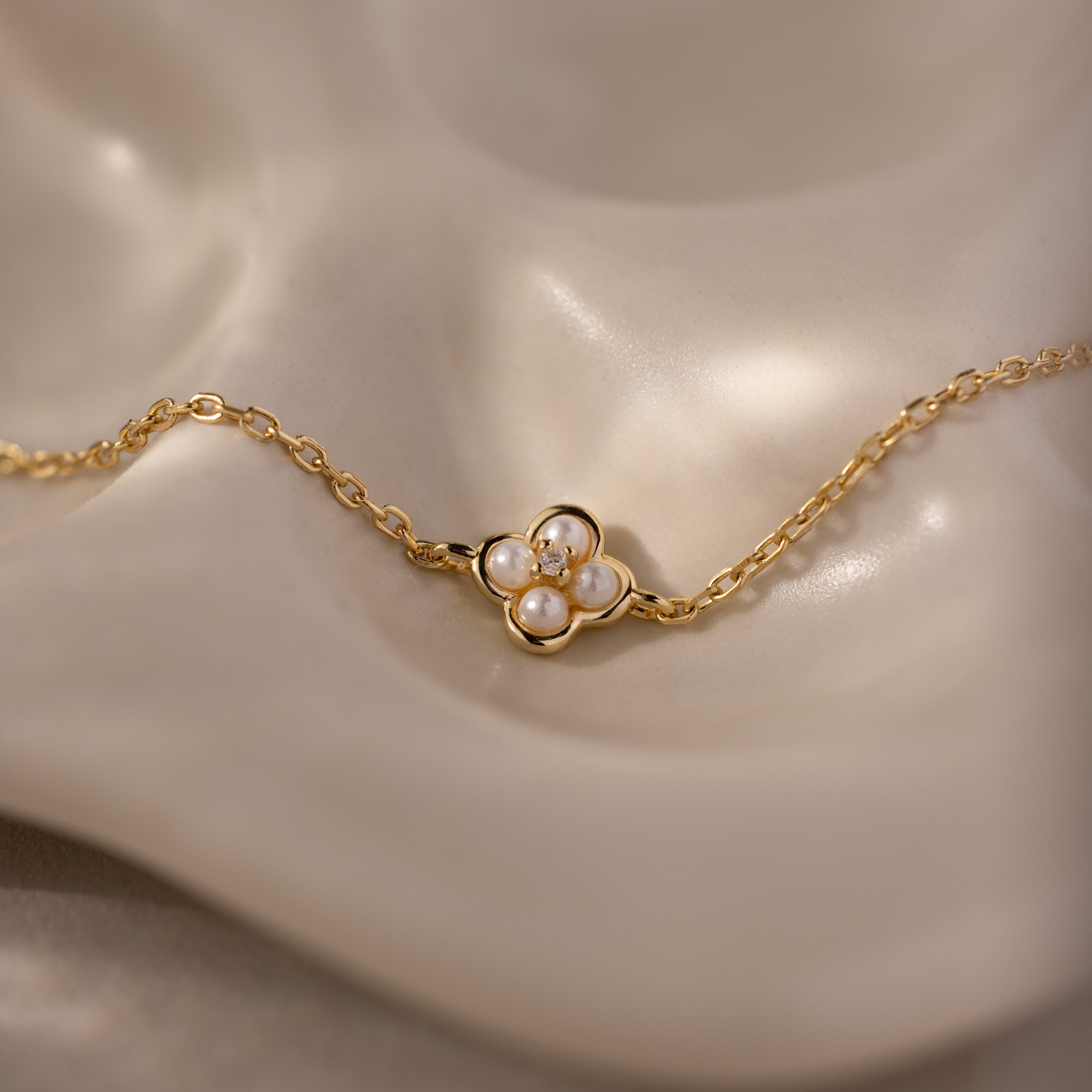 Rounded Pearl Flower Bracelet in 18K Gold features a flower-shaped pendant adorned with four small pearls—an elegant, delicate bracelet perfect for layering with your favorite accessories.