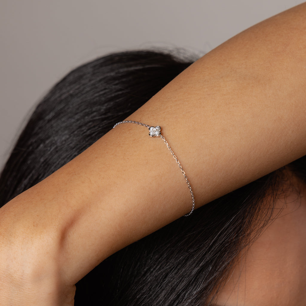 A woman wears the Rounded Pearl Flower Bracelet in Sterling Silver, featuring a delicate floral design and pearl charm, as she raises her arm near her head.