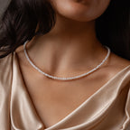 A woman wears the Summer Pearl Beaded Necklace in 18K Gold, styled with a silky, champagne-colored draped top.