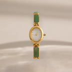 Jade Band Timepiece featuring a minimalist oval gold dial and an elegant green jade band, displayed on a neutral background.