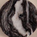 The Onyx Marble Jewelry Dish features round, marbled stone with swirling black, white, and gray patterns on a beige background. Ideal as a marble jewelry dish or stylish holder for your accessories.