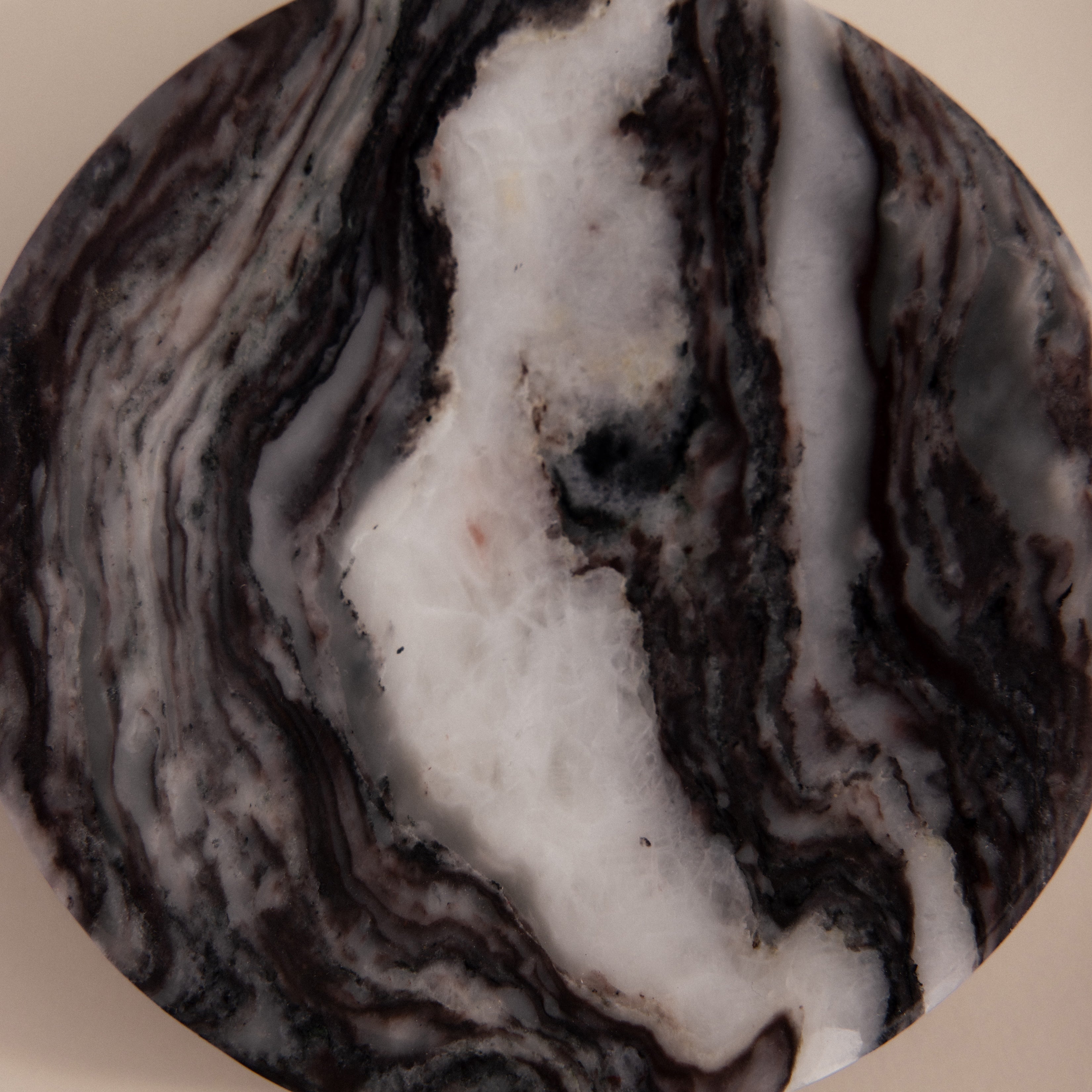 The Onyx Marble Jewelry Dish features round, marbled stone with swirling black, white, and gray patterns on a beige background. Ideal as a marble jewelry dish or stylish holder for your accessories.