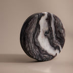 The Onyx Marble Jewelry Dish features swirling black, gray, and white patterns on a beige background—an elegant, polished round holder for your jewelry.