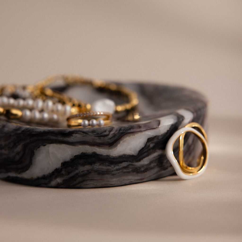 Gold and pearl jewelry displayed on the Onyx Marble Jewelry Dish against a beige background, making it a stylish and elegant jewelry holder.