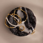 Gold and pearl jewelry displayed on a Marble Jewelry Dish featuring a black and white marbled surface.