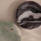 Two Onyx Marble Jewelry Dishes, one in gray-black and the other in green-white, rest elegantly on a beige surface.